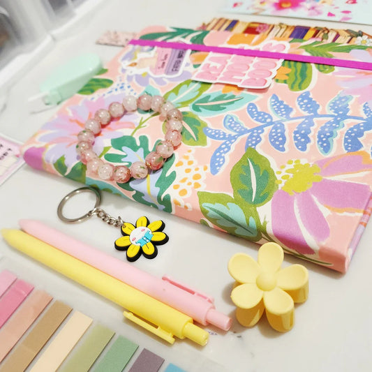 Floral notebook, pens, keychain, and flower-shaped items on a white surface